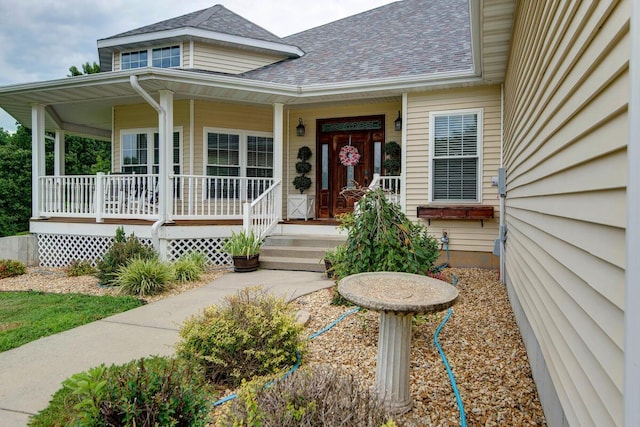 entrance to property with a porch and a shingled roof