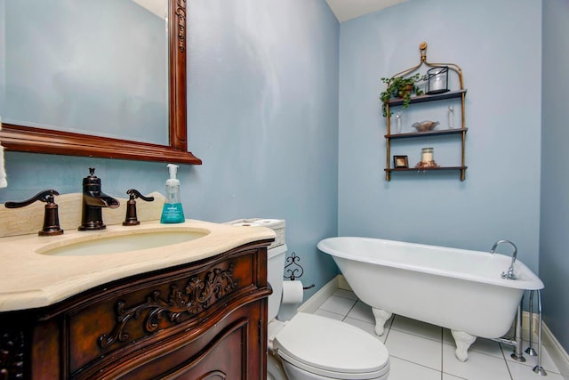 bathroom featuring toilet, a freestanding tub, tile patterned floors, baseboards, and vanity