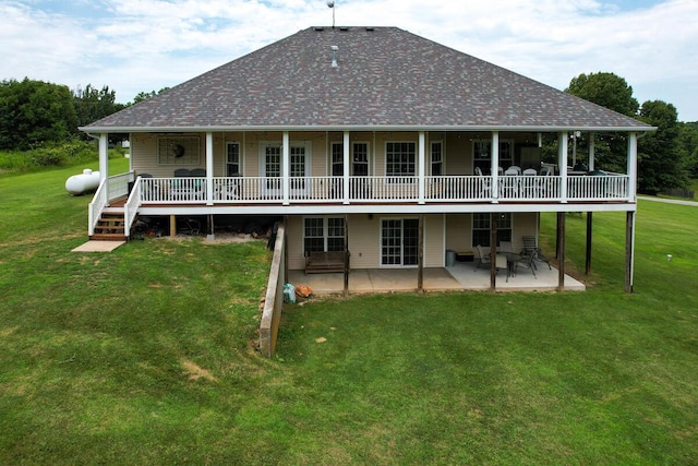 rear view of property featuring a patio area, roof with shingles, a lawn, and a wooden deck