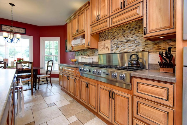 kitchen with decorative backsplash, a chandelier, brown cabinets, stainless steel gas stovetop, and dark countertops