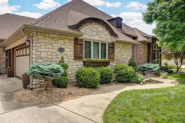 6046 S Parkhaven Ln, Springfield, MO 65810 - french country home featuring stone siding, an attached garage, a shingled roof, driveway, and a front lawn