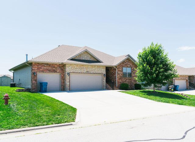 1205 N 12th Ave, Ozark, MO 65721 - view of front of home with a front yard, a garage, driveway, and brick siding