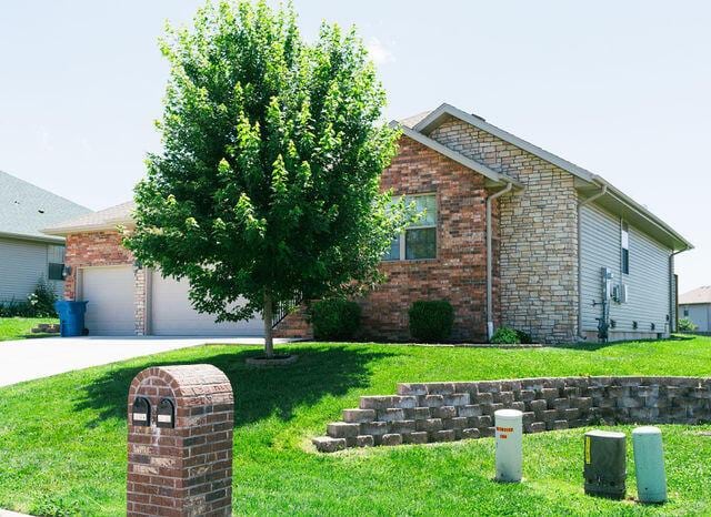 1205 N 12th Ave, Ozark, MO 65721 - view of front of house featuring a front yard, brick siding, and driveway