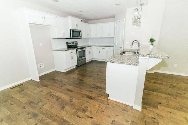 1205 N 12th Ave, Ozark, MO 65721 - kitchen with appliances with stainless steel finishes, light stone countertops, dark wood-style flooring, white cabinets, and hanging light fixtures