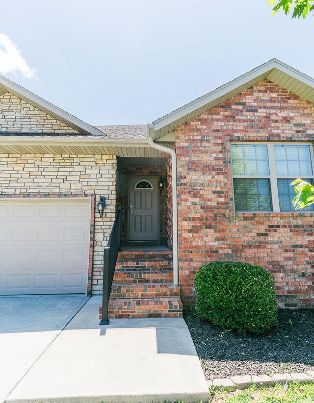 1205 N 12th Ave, Ozark, MO 65721 - view of exterior entry featuring brick siding and an attached garage