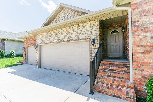 1205 N 12th Ave, Ozark, MO 65721 - property entrance featuring brick siding, a garage, and driveway