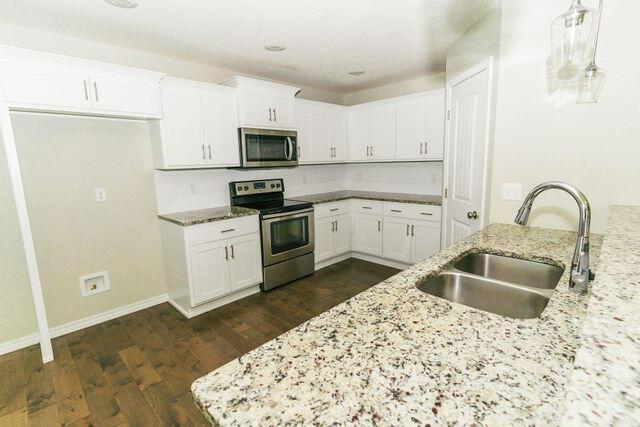 1205 N 12th Ave, Ozark, MO 65721 - kitchen featuring appliances with stainless steel finishes, light stone countertops, dark wood-style floors, and white cabinets