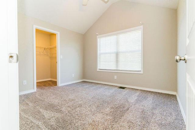 1205 N 12th Ave, Ozark, MO 65721 - unfurnished bedroom with a spacious closet, carpet, vaulted ceiling, a closet, and a ceiling fan