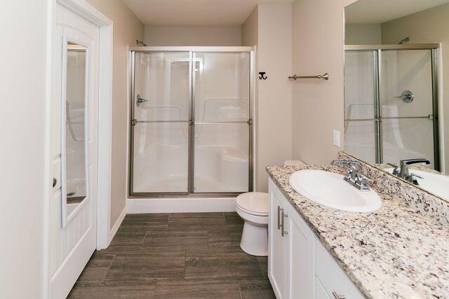 1205 N 12th Ave, Ozark, MO 65721 - bathroom featuring a shower with shower door, vanity, and wood finished floors