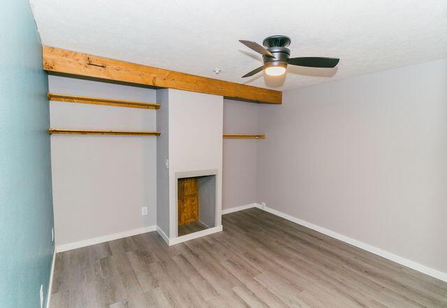 1205 N 12th Ave, Ozark, MO 65721 - unfurnished bedroom featuring a fireplace, wood finished floors, and a ceiling fan
