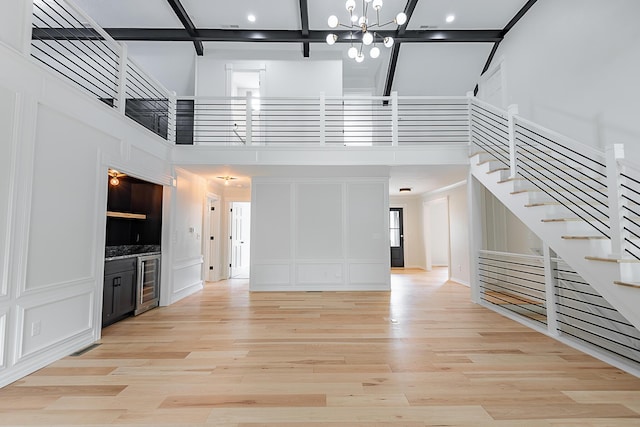 1935 E Canterbury St, Springfield, MO 65804 - unfurnished living room featuring a towering ceiling, beverage cooler, stairs, a chandelier, and light wood-style floors