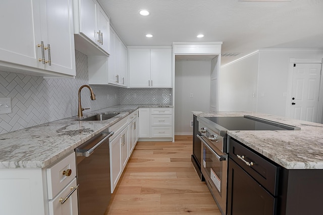 1935 E Canterbury St, Springfield, MO 65804 - kitchen featuring stainless steel appliances, a sink, light wood-type flooring, white cabinetry, and backsplash