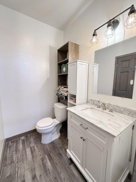 30285 E Pawhuska Rd, El Dorado Springs, MO 64744 - half bathroom with wood finished floors, toilet, vanity, and baseboards