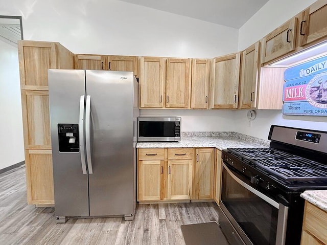 30285 E Pawhuska Rd, El Dorado Springs, MO 64744 - kitchen featuring appliances with stainless steel finishes, light wood-style flooring, light brown cabinets, lofted ceiling, and light stone counters