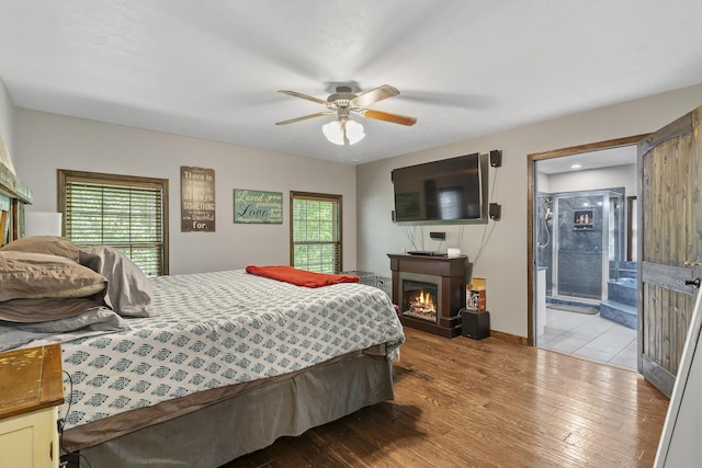 45 Stone Ridge Ct, Strafford, MO 65757 - bedroom featuring a lit fireplace, light wood-type flooring, baseboards, and a ceiling fan