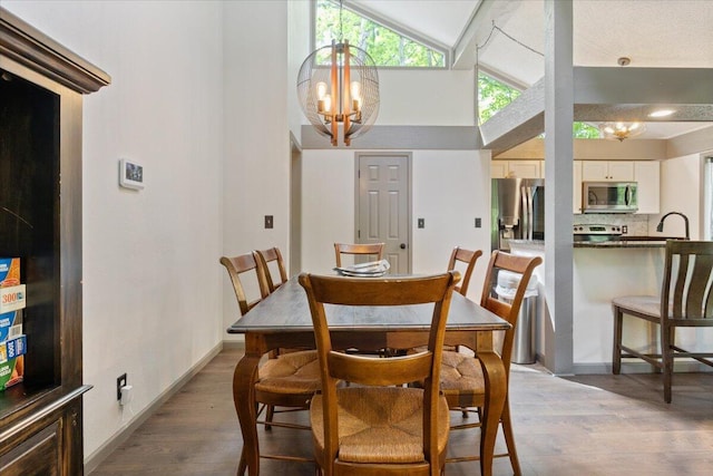 91 Moongate Dr, Osage Beach, MO 65065 - dining room featuring light wood-style floors, a chandelier, high vaulted ceiling, and baseboards