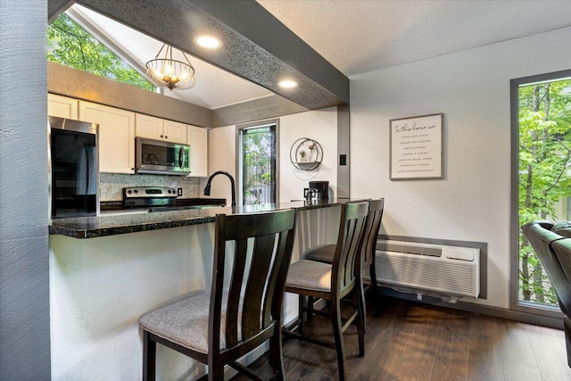 91 Moongate Dr, Osage Beach, MO 65065 - kitchen with appliances with stainless steel finishes, lofted ceiling, white cabinetry, dark wood finished floors, and tasteful backsplash