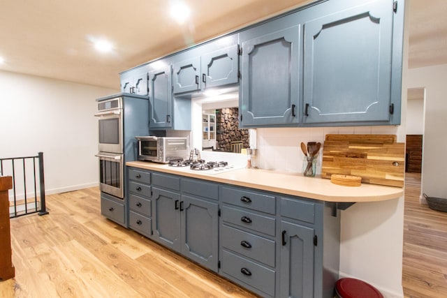 5312 S Hawthorne Dr, Springfield, MO 65804 - kitchen featuring double oven, white gas cooktop, light wood-type flooring, decorative backsplash, and light countertops