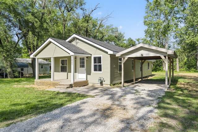 1827 N Tyler Ave, Springfield, MO 65802 - view of front of property with gravel driveway, a detached carport, a shingled roof, a front lawn, and a porch