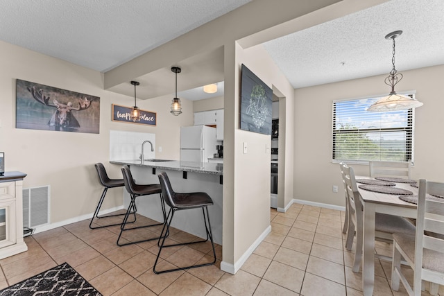 13 Treehouse Ln Unit 4, Branson, MO 65616 - kitchen featuring freestanding refrigerator, a textured ceiling, light tile patterned flooring, a sink, and baseboards