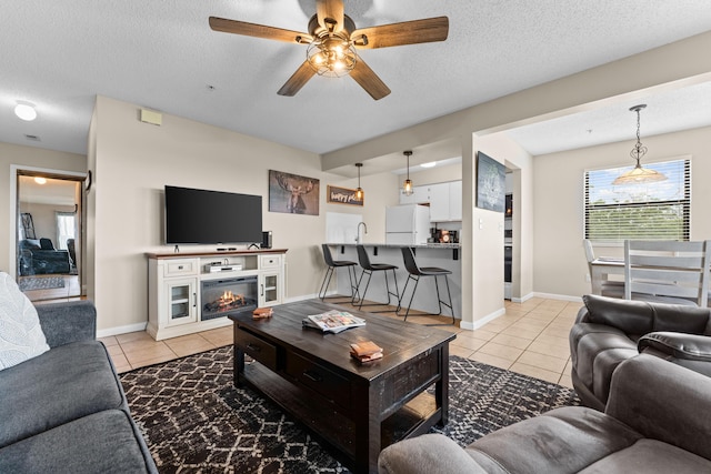 13 Treehouse Ln Unit 4, Branson, MO 65616 - living area with light tile patterned floors, a ceiling fan, a textured ceiling, baseboards, and a glass covered fireplace