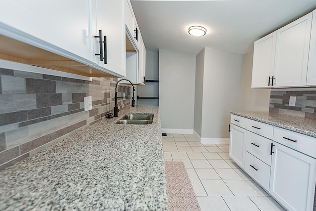 1223 W State St, Springfield, MO 65806 - kitchen featuring a sink, decorative backsplash, light stone counters, and white cabinetry