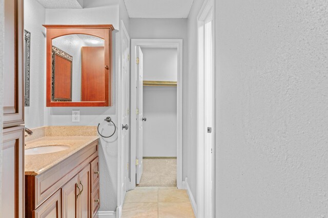 4824 S Gold Rd, Battlefield, MO 65619 - bathroom with vanity, tile patterned floors, a textured wall, and a walk in closet