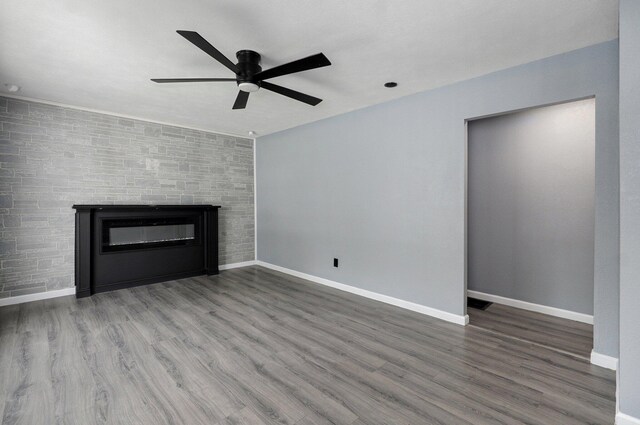 2418 E Catalpa St, Springfield, MO 65804 - unfurnished living room featuring a ceiling fan, a glass covered fireplace, wood finished floors, and baseboards