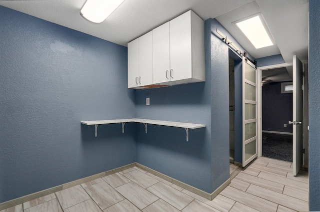 2418 E Catalpa St, Springfield, MO 65804 - clothes washing area featuring a barn door, baseboards, a textured wall, and wood finish floors