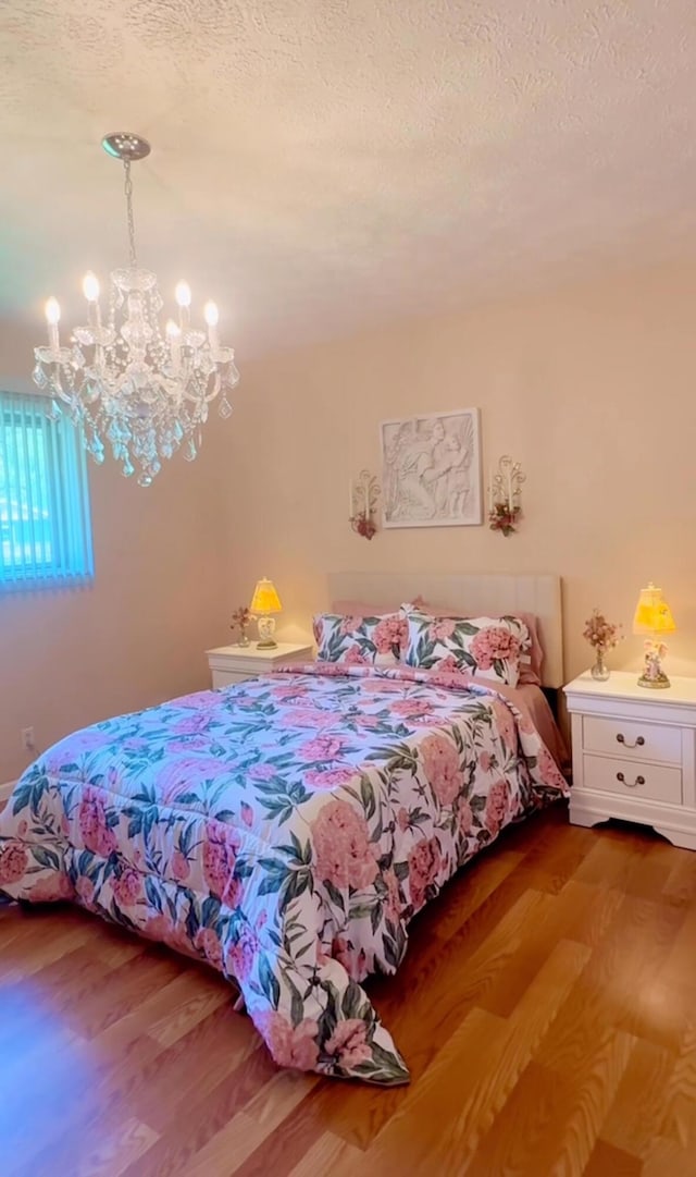 bedroom featuring wood finished floors, a chandelier, and a textured ceiling