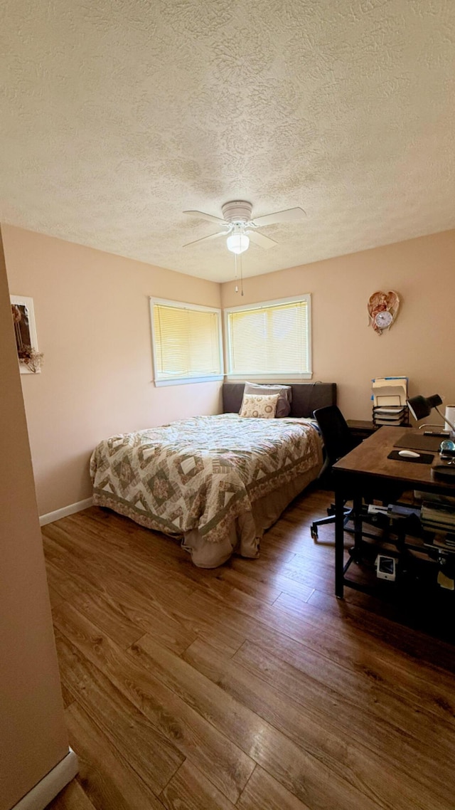 bedroom with a textured ceiling, wood finished floors, ceiling fan, and baseboards