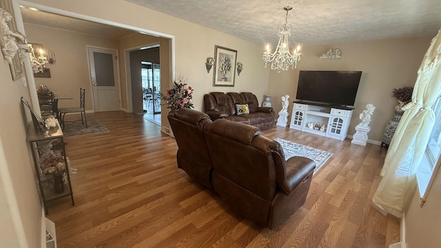 living room featuring a chandelier, wood finished floors, baseboards, and a textured ceiling