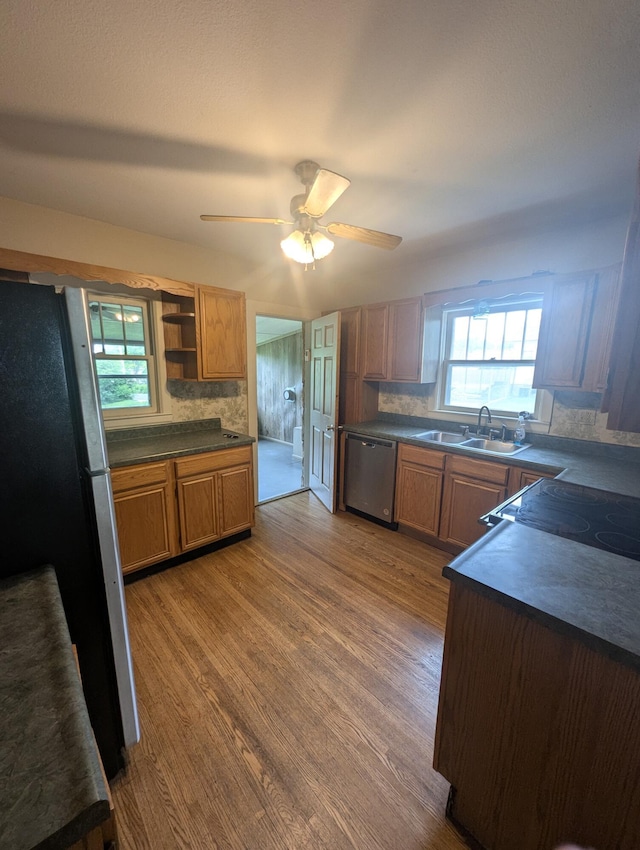 1301 W Main St, West Plains, MO 65775 - kitchen featuring stainless steel appliances, dark countertops, a sink, wood finished floors, and backsplash