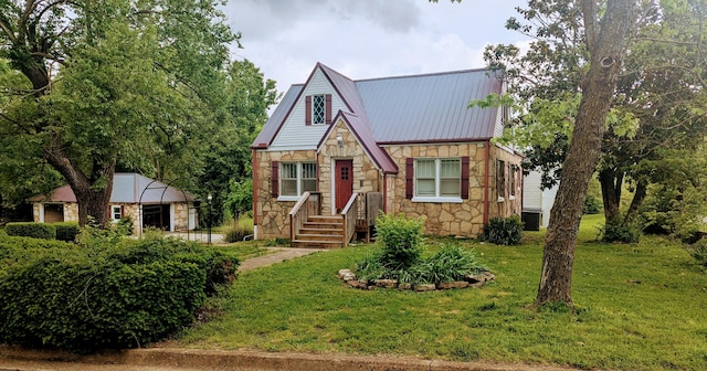 1301 W Main St, West Plains, MO 65775 - english style home featuring stone siding, a front yard, metal roof, and central air condition unit