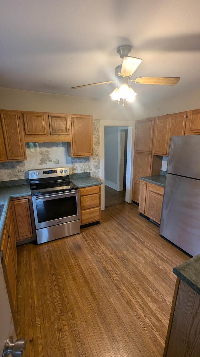 1301 W Main St, West Plains, MO 65775 - kitchen with appliances with stainless steel finishes, dark wood-type flooring, dark countertops, ceiling fan, and brown cabinetry