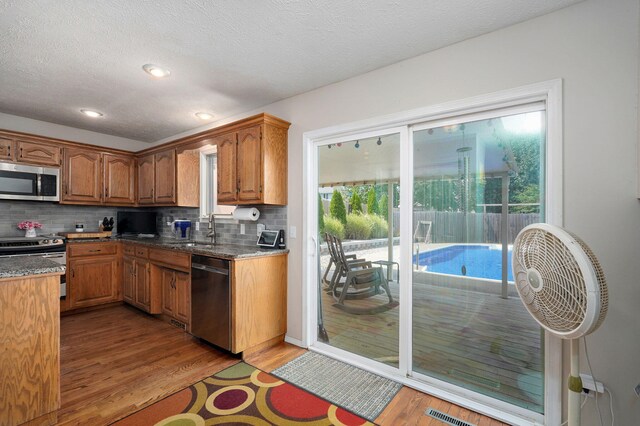 2019 N Preakness Dr, Nixa, MO 65714 - kitchen featuring appliances with stainless steel finishes, a sink, wood finished floors, tasteful backsplash, and a textured ceiling