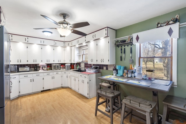 1529 S Jefferson Ave, Aurora, MO 65605 - kitchen with a sink, a ceiling fan, backsplash, white cabinets, and light wood-style floors