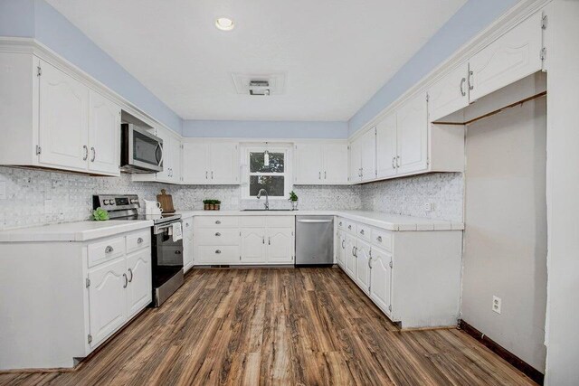 3729 S Parklane Ave, Springfield, MO 65807 - kitchen featuring appliances with stainless steel finishes, a sink, dark wood-style flooring, white cabinetry, and tasteful backsplash