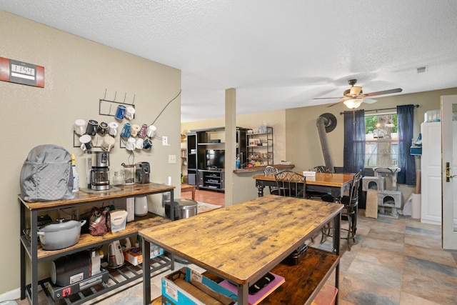 1356 State Highway 32, Long Lane, MO 65590 - dining room with ceiling fan, a wood stove, a textured ceiling, and light stone finish flooring
