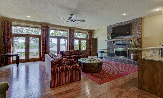 1605 Hideaway Rd, Galena, MO 65656 - living room featuring a textured ceiling, ornamental molding, wood-type flooring, a ceiling fan, and a fireplace