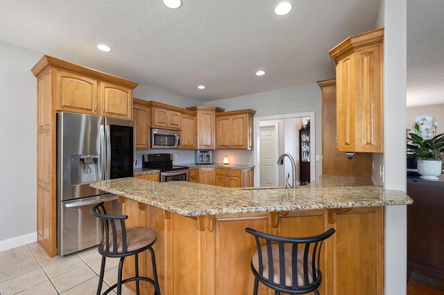 2310 Lakeside Ct, Ozark, MO 65721 - kitchen featuring stainless steel appliances, a peninsula, a breakfast bar, light stone countertops, and recessed lighting