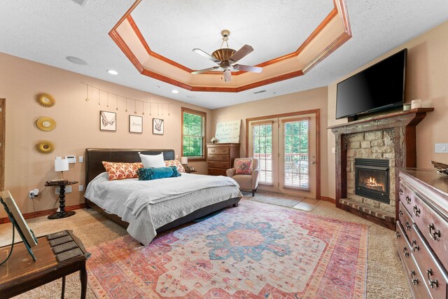 261 Country Bluff Dr, Branson, MO 65616 - bedroom with access to exterior, a stone fireplace, light colored carpet, a tray ceiling, and a textured ceiling