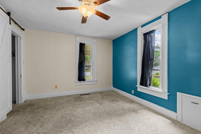 537 S Jefferson Ave, Aurora, MO 65605 - carpeted empty room with a textured ceiling, a ceiling fan, a barn door, and baseboards