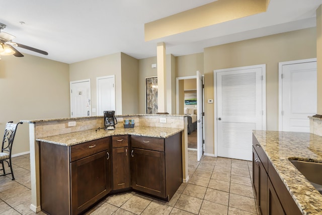 2800 Green Mountain Dr Unit 231, Branson, MO 65616 - kitchen with a ceiling fan, dark brown cabinets, light stone countertops, light tile patterned flooring, and a center island