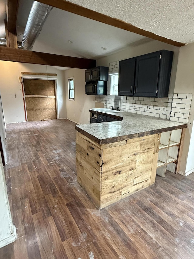 911 W Locust St, Springfield, MO 65803 - kitchen featuring black microwave, dark wood-style flooring, decorative backsplash, a peninsula, and dark cabinets