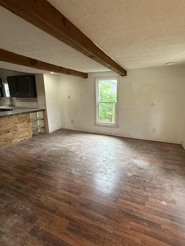 911 W Locust St, Springfield, MO 65803 - unfurnished living room with a textured ceiling, dark wood finished floors, and beam ceiling