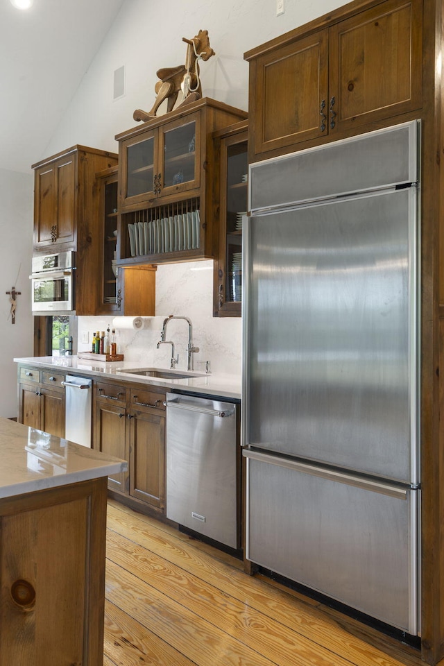 1007 Headwaters Dr, Marshfield, MO 65706 - kitchen with appliances with stainless steel finishes, a sink, lofted ceiling, light wood finished floors, and tasteful backsplash