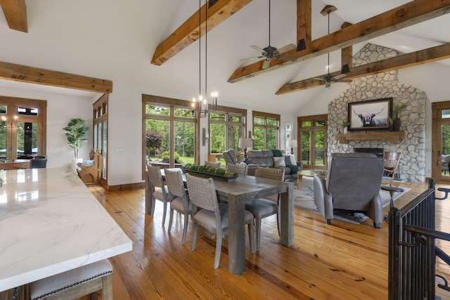1007 Headwaters Dr, Marshfield, MO 65706 - dining area with beamed ceiling, a ceiling fan, light wood-type flooring, a stone fireplace, and baseboards