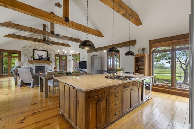 1007 Headwaters Dr, Marshfield, MO 65706 - kitchen featuring appliances with stainless steel finishes, a stone fireplace, beamed ceiling, pendant lighting, and a kitchen island
