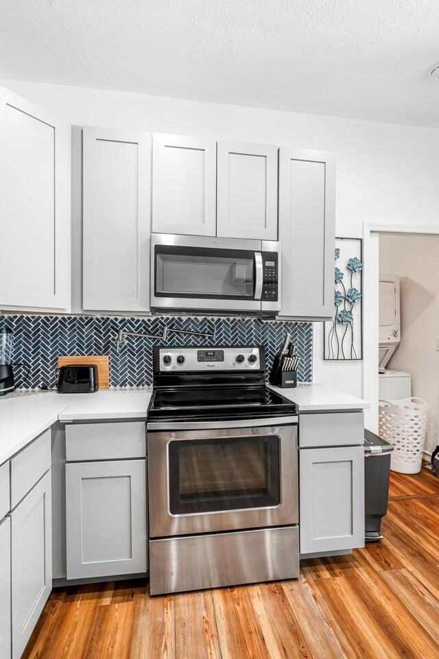 1200 E Walnut St, Springfield, MO 65802 - kitchen with appliances with stainless steel finishes, light countertops, tasteful backsplash, light wood-style flooring, and a textured ceiling